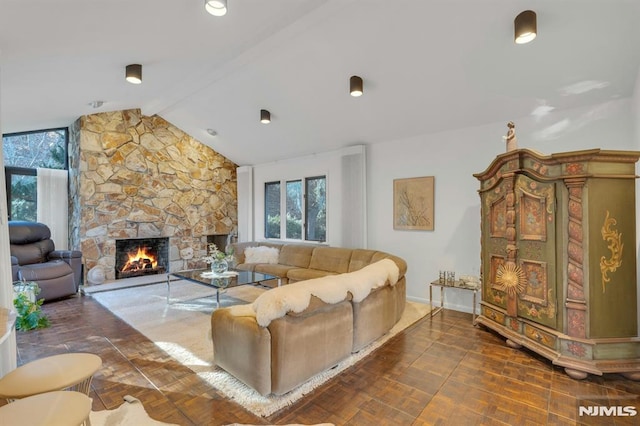 living room with vaulted ceiling with beams and a stone fireplace