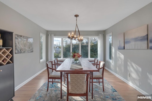 dining room with light hardwood / wood-style flooring and an inviting chandelier