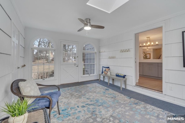 sunroom featuring ceiling fan with notable chandelier