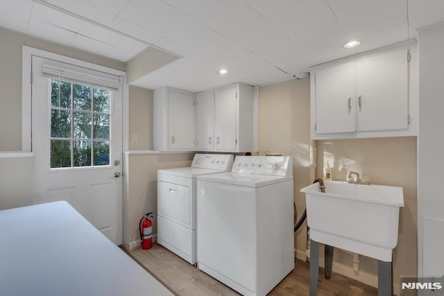 laundry area featuring washer and dryer, cabinets, light hardwood / wood-style flooring, and sink