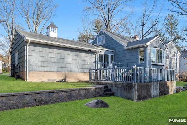 rear view of house featuring a lawn and a wooden deck