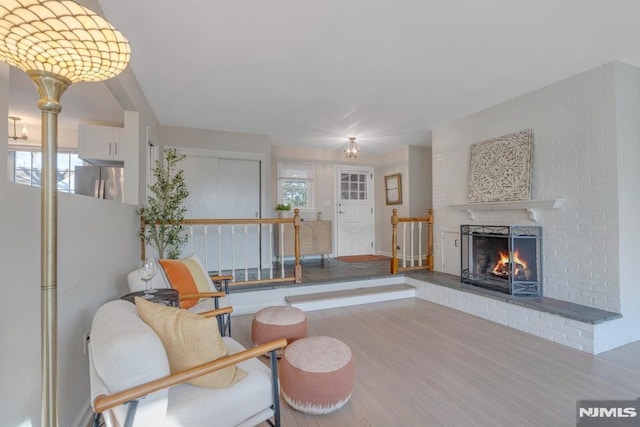 sitting room with a brick fireplace, hardwood / wood-style flooring, and plenty of natural light