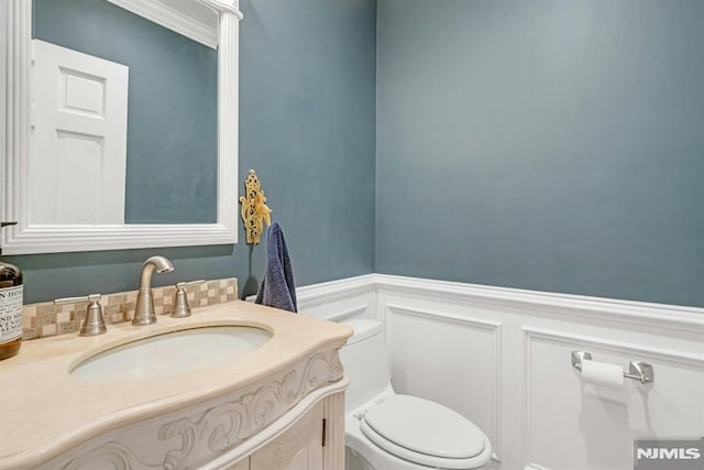 bathroom with crown molding, vanity, and toilet