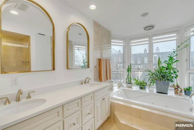 bathroom featuring tiled tub, a wealth of natural light, and vanity