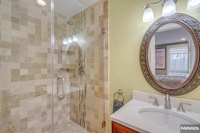 bathroom with a shower with shower door and vanity