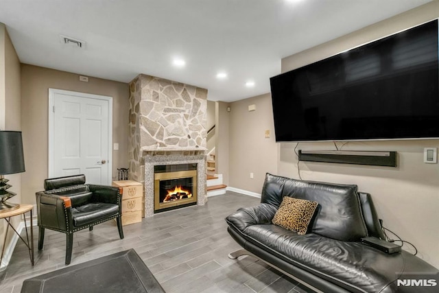 living room with hardwood / wood-style flooring and a stone fireplace