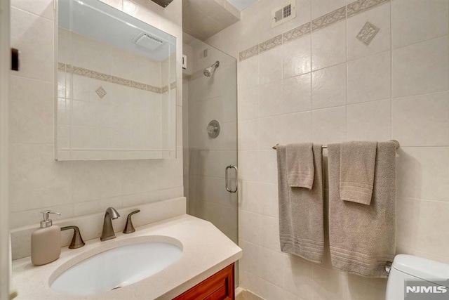 bathroom featuring tile walls, toilet, decorative backsplash, an enclosed shower, and vanity