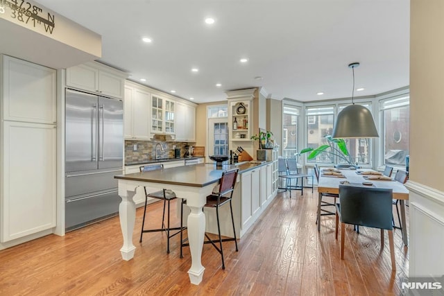 kitchen featuring pendant lighting, light wood-type flooring, white cabinetry, appliances with stainless steel finishes, and a kitchen breakfast bar