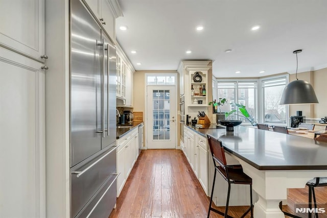 kitchen featuring decorative light fixtures, a breakfast bar area, white cabinets, and appliances with stainless steel finishes