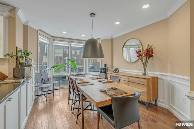 dining space featuring ornamental molding and light hardwood / wood-style flooring