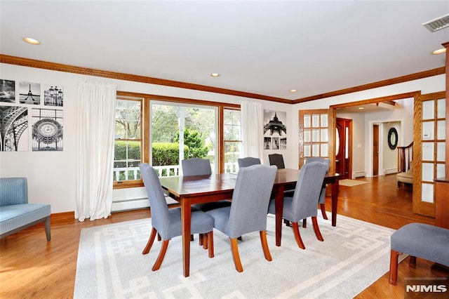 dining area with ornamental molding, light hardwood / wood-style flooring, and a baseboard radiator