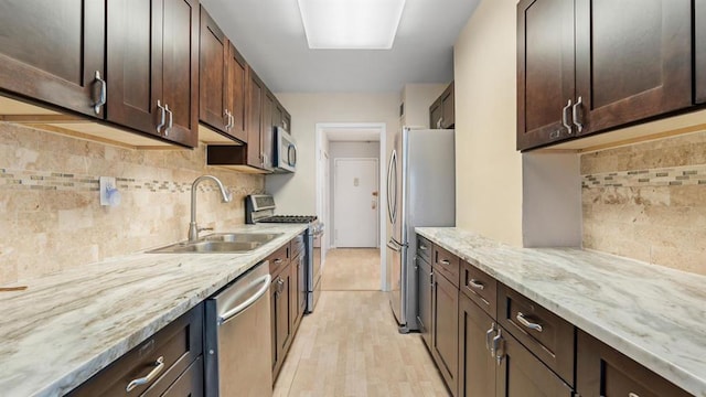 kitchen with appliances with stainless steel finishes, light hardwood / wood-style flooring, dark brown cabinets, and sink