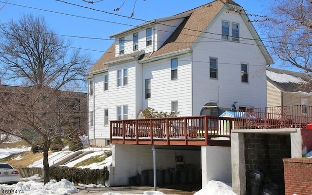 snow covered rear of property featuring a deck