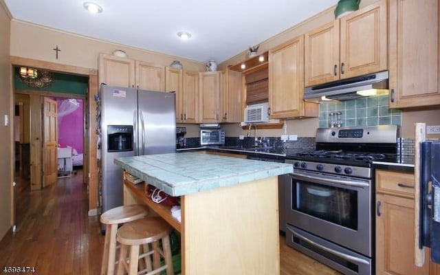 kitchen with tile countertops, a center island, stainless steel appliances, and light brown cabinetry