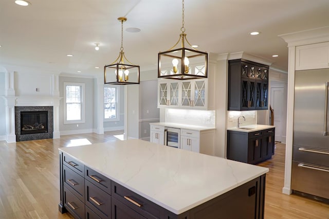 kitchen with a center island, tasteful backsplash, built in refrigerator, decorative light fixtures, and white cabinets