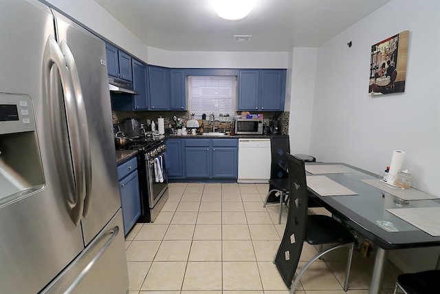 kitchen featuring backsplash, light tile patterned floors, blue cabinetry, and appliances with stainless steel finishes