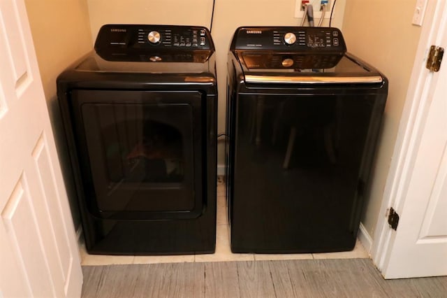 clothes washing area featuring washer and clothes dryer and light hardwood / wood-style floors