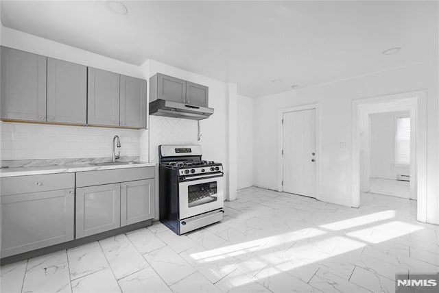 kitchen with tasteful backsplash, gas range, sink, and gray cabinets