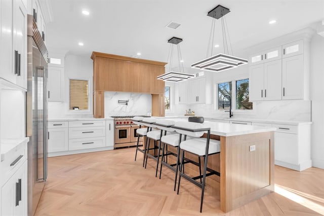 kitchen featuring high end range, light parquet flooring, white cabinetry, and a kitchen island