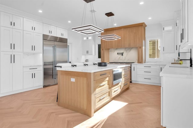 kitchen with light parquet floors, built in appliances, a center island, and white cabinetry