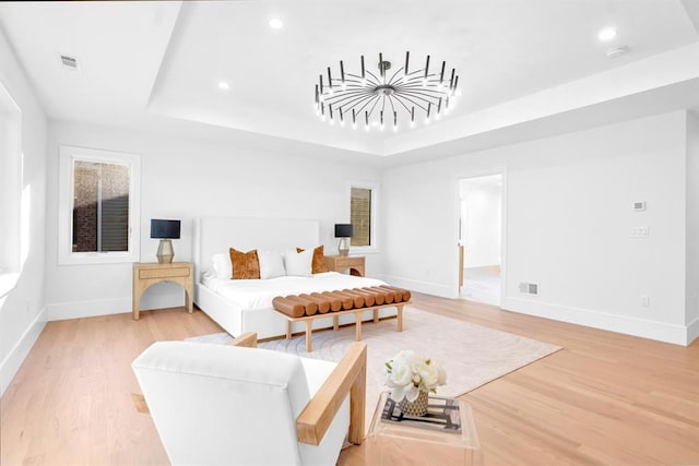 bedroom with hardwood / wood-style floors and a tray ceiling