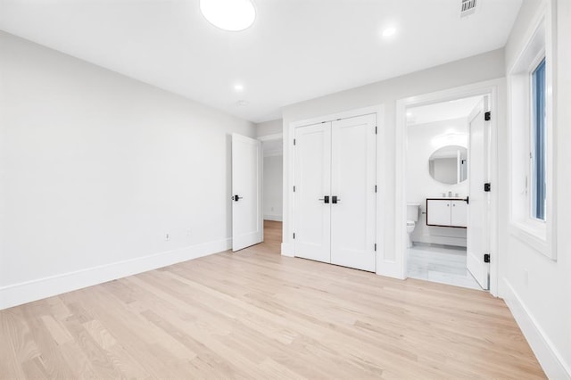 unfurnished bedroom with connected bathroom and light hardwood / wood-style flooring