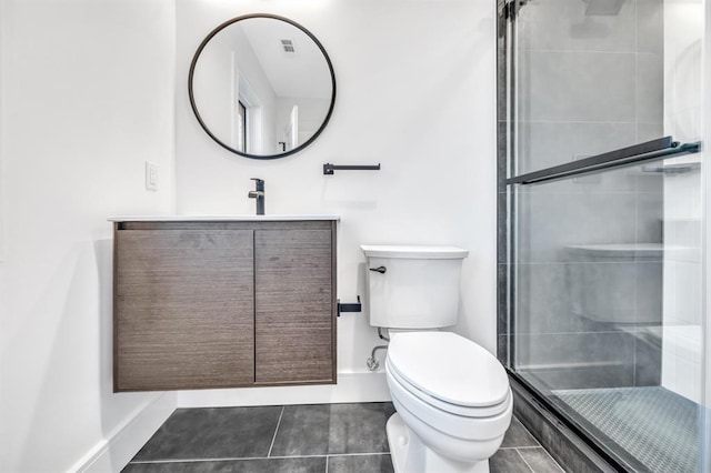 bathroom featuring tile patterned floors, vanity, a shower with shower door, and toilet