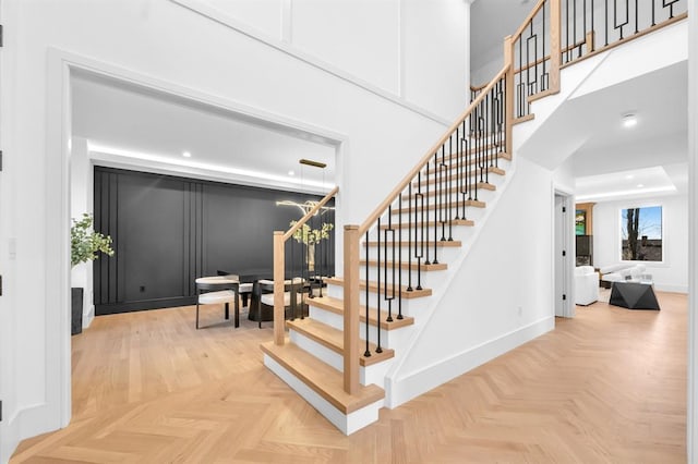 staircase featuring parquet flooring and a chandelier