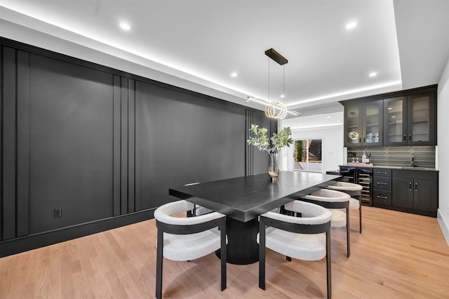 dining area with bar area, light wood-type flooring, and beverage cooler