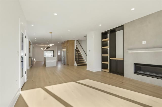 unfurnished living room featuring built in shelves and hardwood / wood-style floors