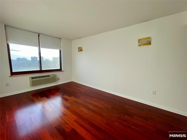 empty room with an AC wall unit and dark wood-type flooring