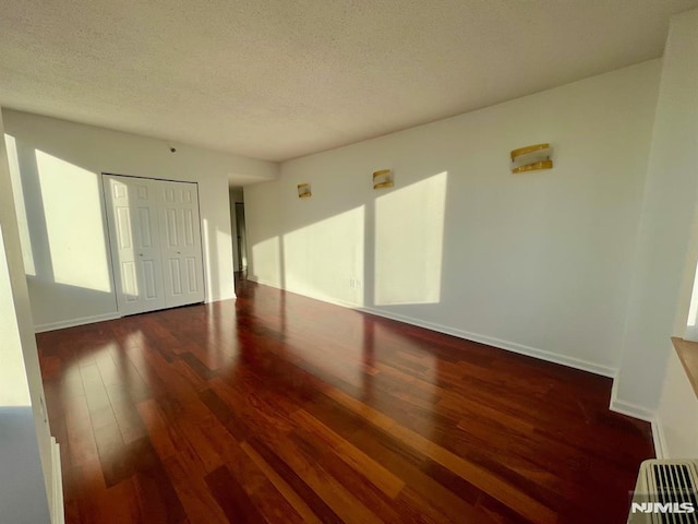 empty room featuring a textured ceiling and dark wood-type flooring