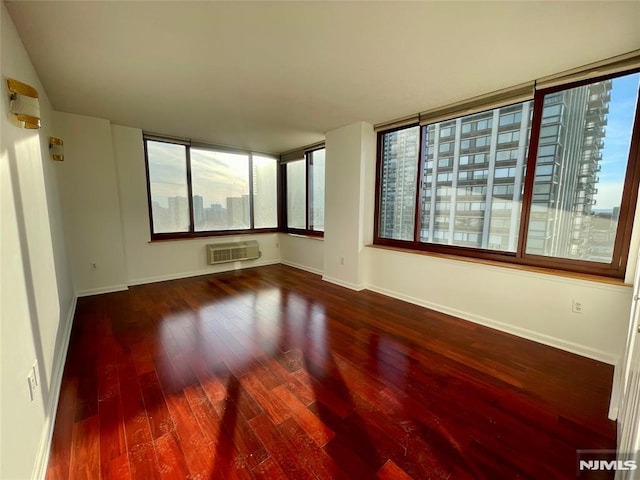 unfurnished room with hardwood / wood-style floors and an AC wall unit