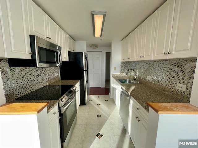 kitchen with decorative backsplash, stainless steel appliances, sink, white cabinetry, and light tile patterned flooring