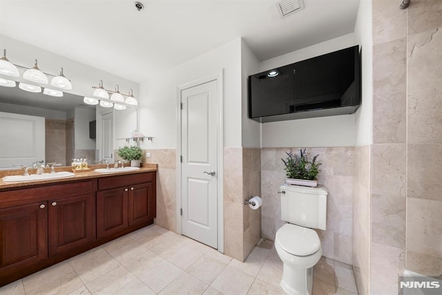 bathroom featuring tile patterned floors, vanity, tile walls, and toilet