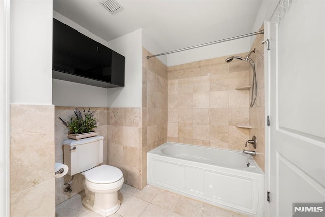 bathroom featuring tile patterned floors, tiled shower / bath combo, tile walls, and toilet