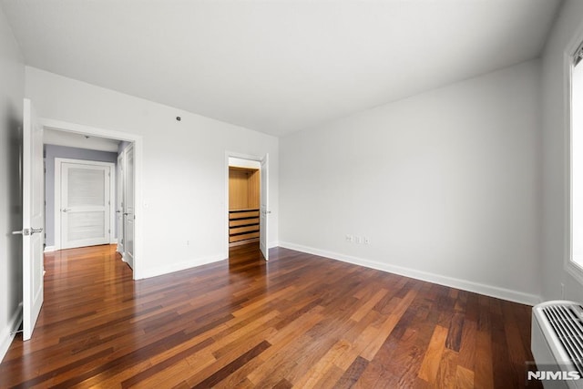 unfurnished bedroom featuring a closet, dark hardwood / wood-style floors, a spacious closet, and a wall mounted AC