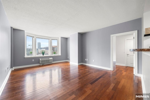 unfurnished living room featuring a textured ceiling, dark hardwood / wood-style floors, and a wall unit AC