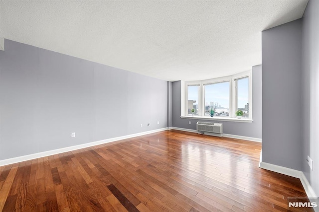 unfurnished living room featuring hardwood / wood-style floors, a textured ceiling, and a wall mounted AC