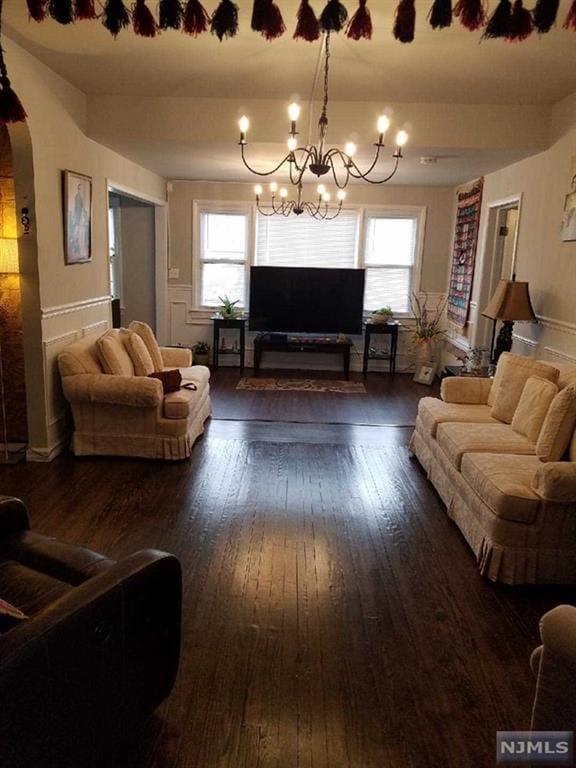 living room featuring a healthy amount of sunlight, dark wood-type flooring, and a chandelier