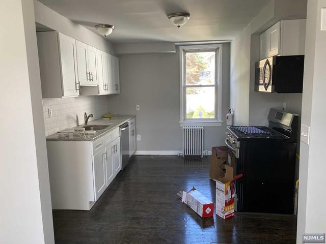 kitchen featuring white cabinets, stainless steel appliances, radiator, and sink