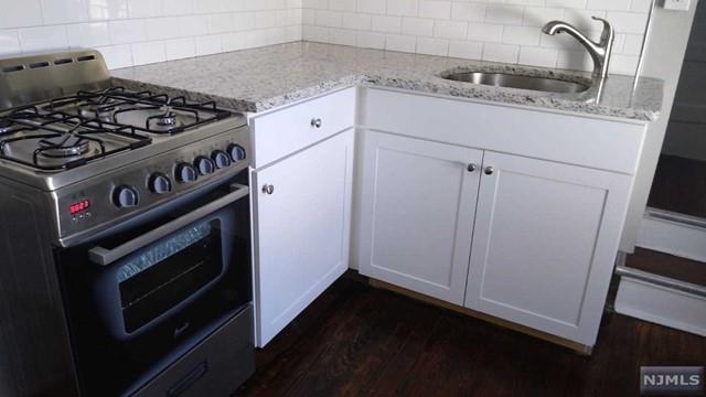 kitchen with stainless steel range, backsplash, white cabinetry, and sink