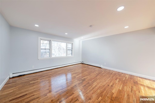 empty room with light hardwood / wood-style floors and a baseboard heating unit