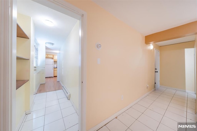 corridor with light tile patterned floors and a baseboard heating unit