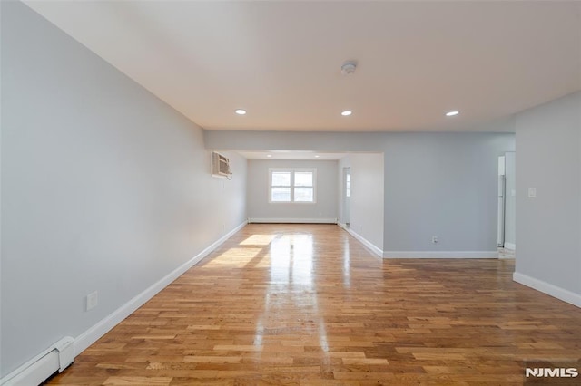 spare room featuring light hardwood / wood-style floors, an AC wall unit, and a baseboard heating unit