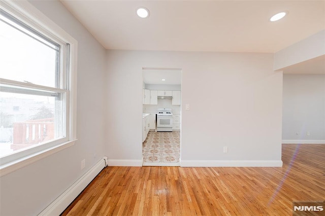 unfurnished room featuring light wood-type flooring and baseboard heating