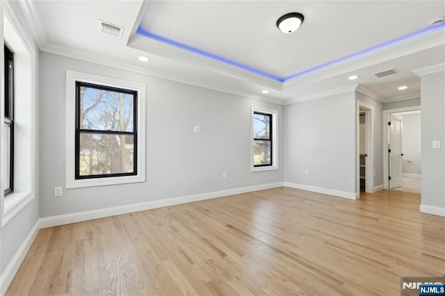 unfurnished room featuring crown molding, a tray ceiling, and light hardwood / wood-style floors