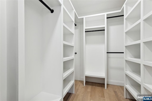 walk in closet with light hardwood / wood-style floors