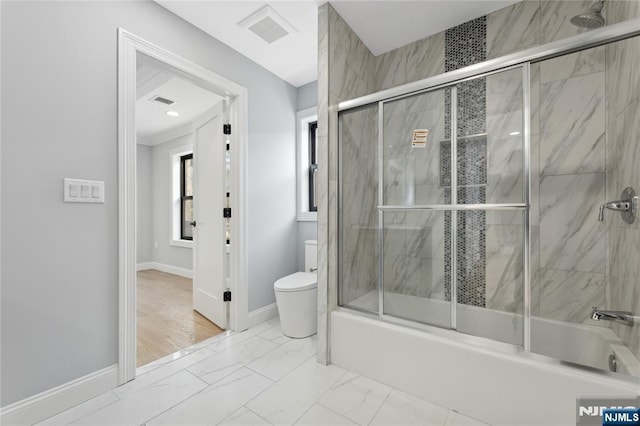 bathroom with bath / shower combo with glass door and toilet