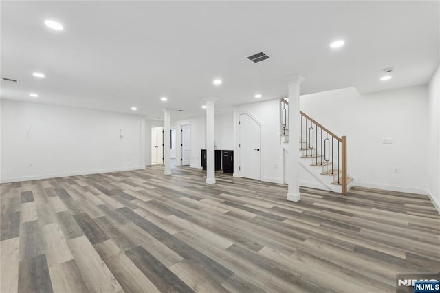 unfurnished living room featuring decorative columns and light hardwood / wood-style floors